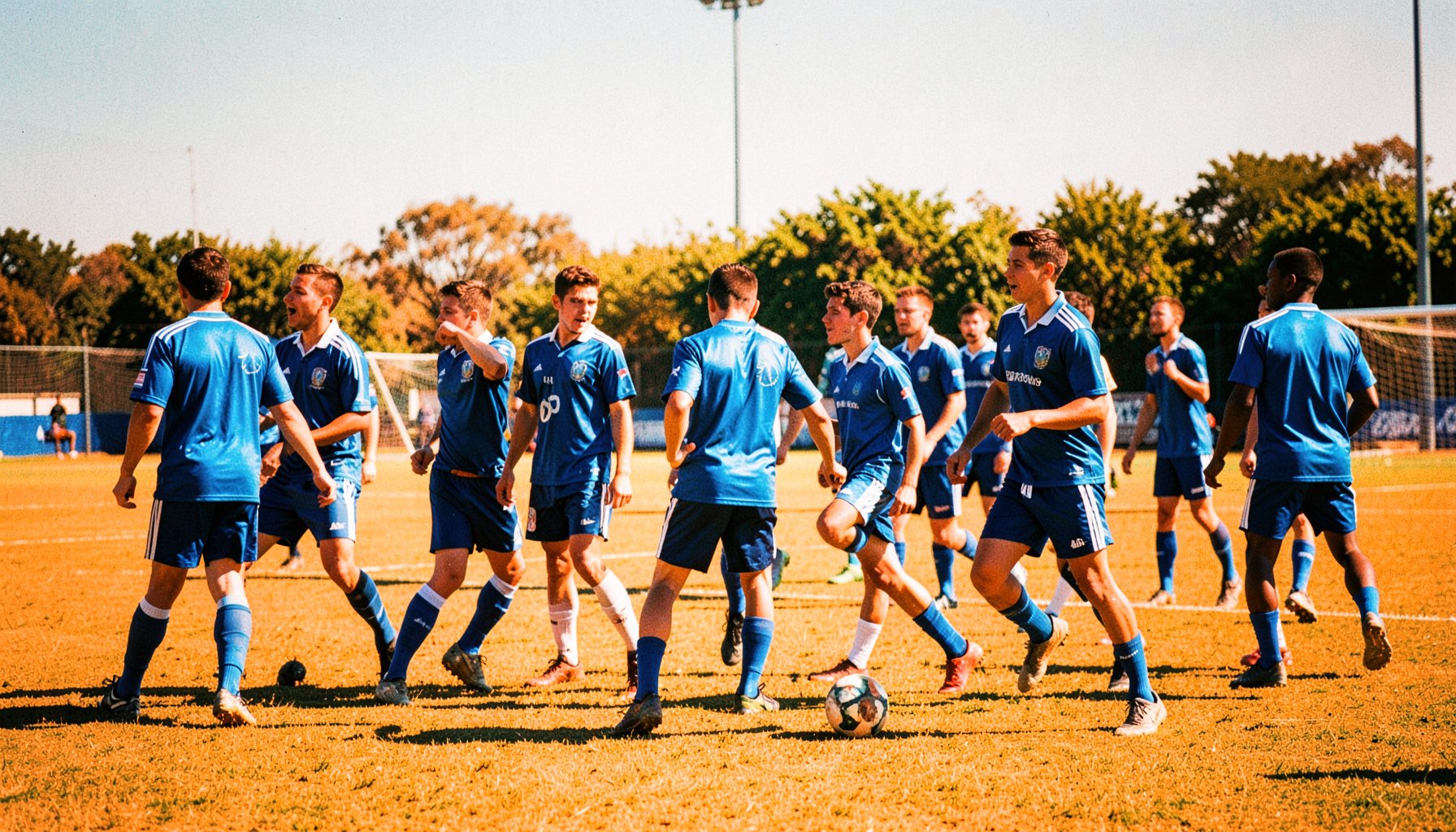 Equipo deportivo universitario en una cancha al aire libre, uniformes azules, día soleado, espíritu competitivo.